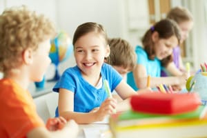 Portrait of happy pupil looking at her classmate at lesson